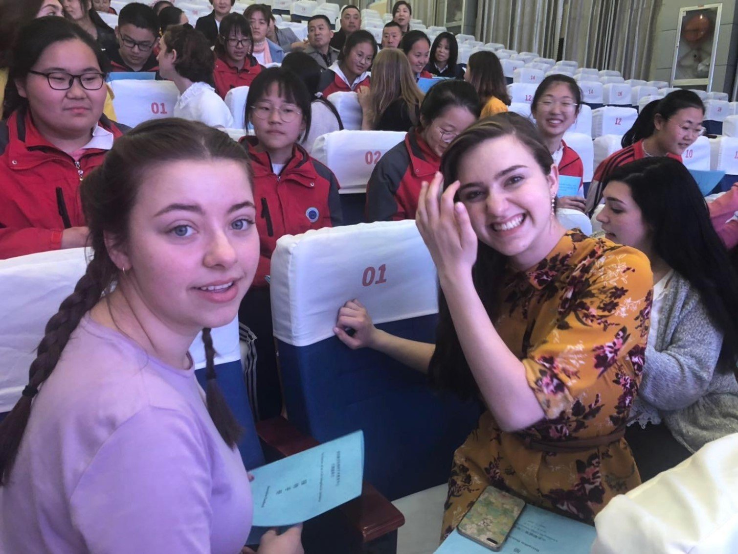 Student Study Tour Group members and Chinese students smile for a picture at an auditorium.